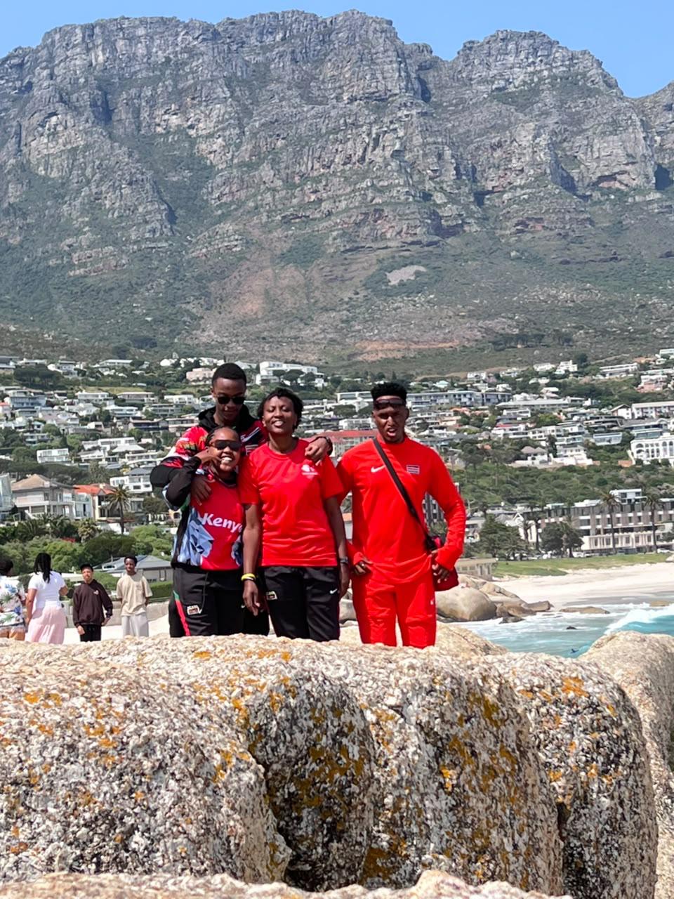 Four Kenya team members posing by the coast with Table Mountain behind them